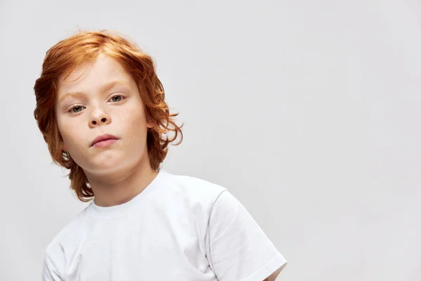 Bambino dai capelli rossi in una t-shirt bianca viso primo piano ritagliato con spazio copia — Foto Stock
