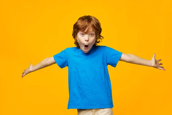 Κόκκινο-μαλλιά αγόρι κρατώντας τα χέρια σε διαφορετικές κατευθύνσεις έκπληξη συναισθήματα μπλε t-shirt παιδική ηλικία Copy Space — Φωτογραφία Αρχείου