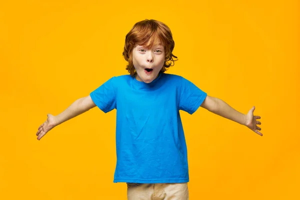 Glada pojke ler mot kameran gest med händerna till hand överraskning barndom blå t-shirt — Stockfoto