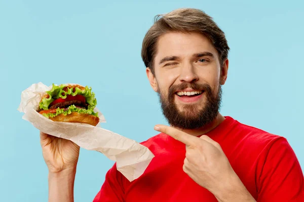 Muž s hamburgerem v rukou stravy s rychlým občerstvením — Stock fotografie