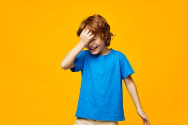 Kızıl saçlı, çilli çocuk. Kızıl saçlı bir çocuk elini yüzünde tutuyor. Üzüntü. 