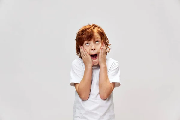 Rudy chłopiec w t-shirt trzyma jego emocje twarz — Zdjęcie stockowe