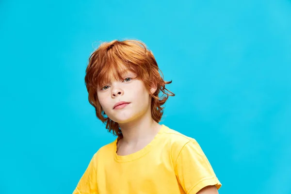 Un bambino con i capelli rossi e in una t-shirt gialla su uno sfondo isolato vista ritagliata — Foto Stock