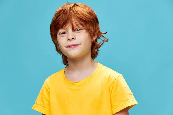 Uśmiechnięty chłopiec z czerwonymi włosami na niebieskim tle — Zdjęcie stockowe
