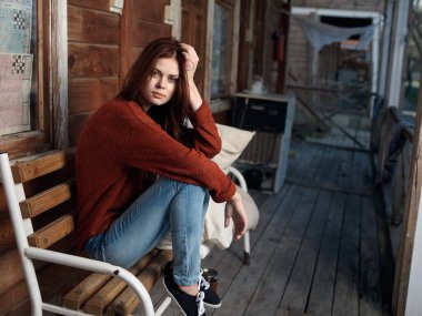 Kadın terasta bankta oturuyor, boş zamanlarında temiz hava alıyor.