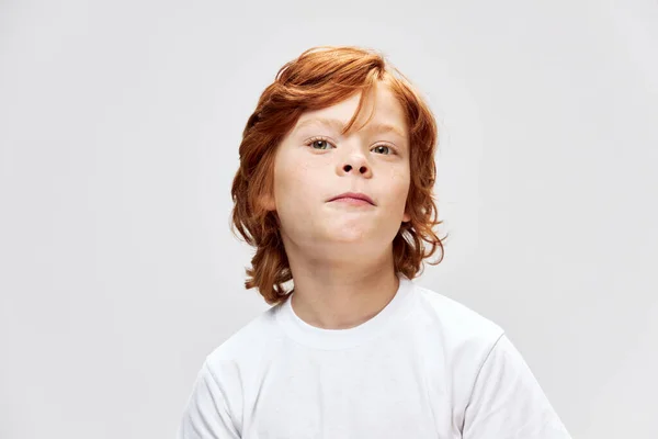 Rödhårig pojke i vit t-shirt beskärd grå bakgrund — Stockfoto