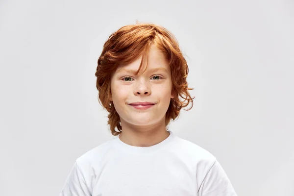 Χαρούμενη κοκκινομάλλα παιδί λευκό t-shirt χαμόγελο Studio γκρι απομονωμένη — Φωτογραφία Αρχείου