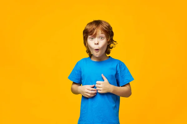 Meglepett vörös hajú fiú kék póló stúdió lövés sárga háttér — Stock Fotó