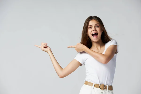Эмоциональная женщина с открытым ртом показывает пальцы в сторону белой белой футболки — стоковое фото