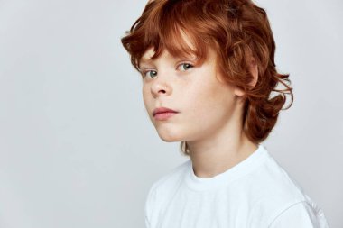 Redheaded child face close-up cropped view of white t-shirt freckles on the face clipart