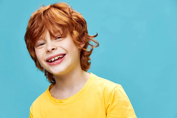 Κόκκινο αγόρι γελάει σε ένα απομονωμένο φόντο σε ένα κίτρινο T-shirt — Φωτογραφία Αρχείου