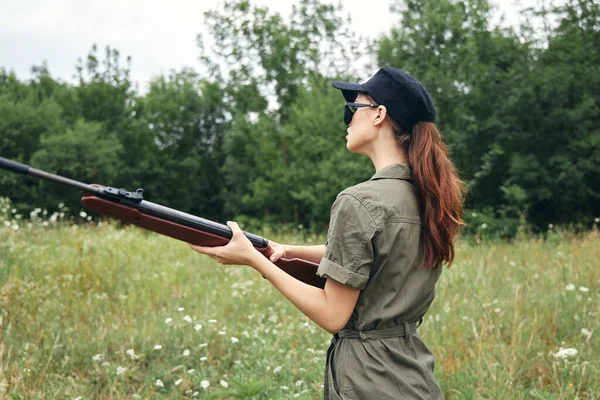 Militar mujer con un arma en las manos gafas de sol mono verde — Foto de Stock