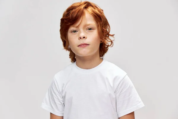 Adolescente rousse en t-shirt blanc regarde vers l'avant fond gris — Photo