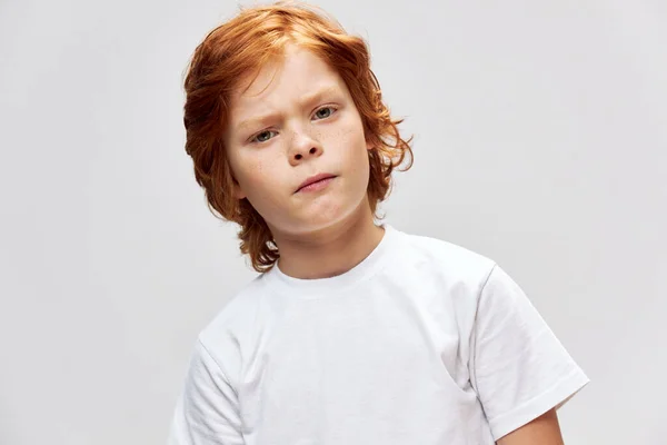 Zrzavý teenager v bílém tričku oříznutý pohled na šedé pozadí — Stock fotografie