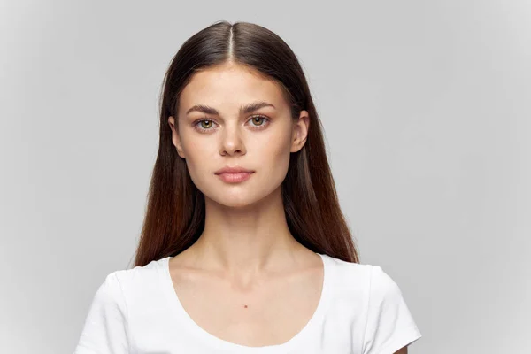 Retrato de una mujer sobre un fondo claro en una camiseta y cabello suelto —  Fotos de Stock