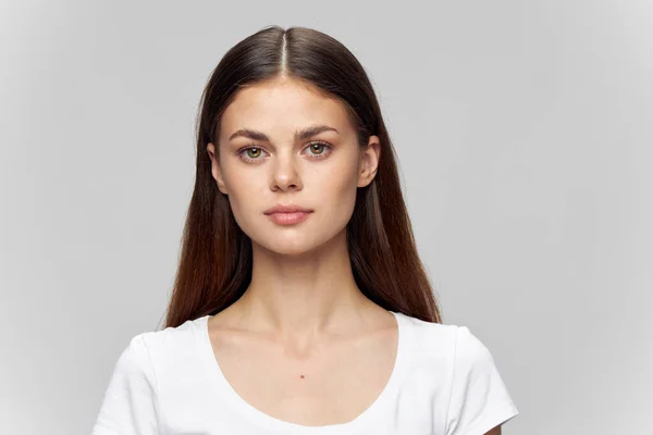 Retrato de uma mulher em um fundo claro em uma camiseta e cabelo solto — Fotografia de Stock