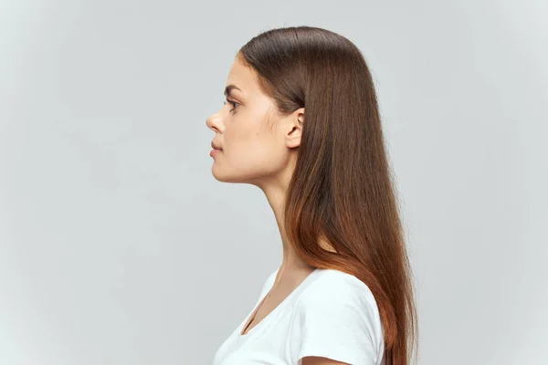 A brunette in a light T-shirt on an isolated background looks into the distance — Stock Photo, Image