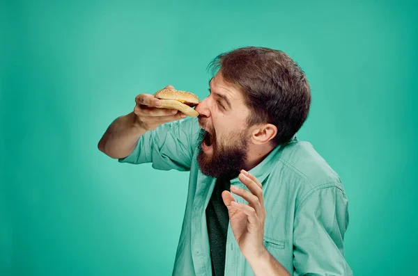Férfi zöld ingben hamburger eszik gyorsétterem életmód — Stock Fotó