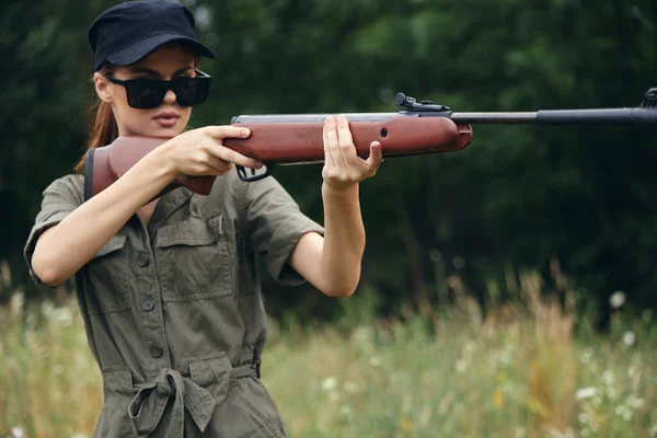 Mujer sosteniendo un arma apuntando gafas de sol hojas verdes — Foto de Stock