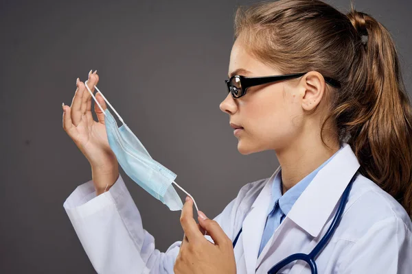 Жінка-лікар в медичній сукні зі стетоскопом навколо її шиї шприц ін'єкції окуляри внутрішній сірий фон — стокове фото