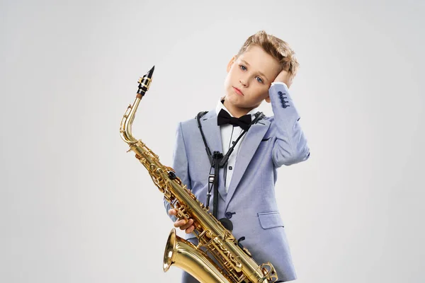 Jongen muzikant in een pak speelt de saxofoon — Stockfoto