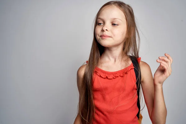 Χαριτωμένο κοριτσάκι με κόκκινο μπλουζάκι και σακίδιο στην παιδική της ηλικία. — Φωτογραφία Αρχείου