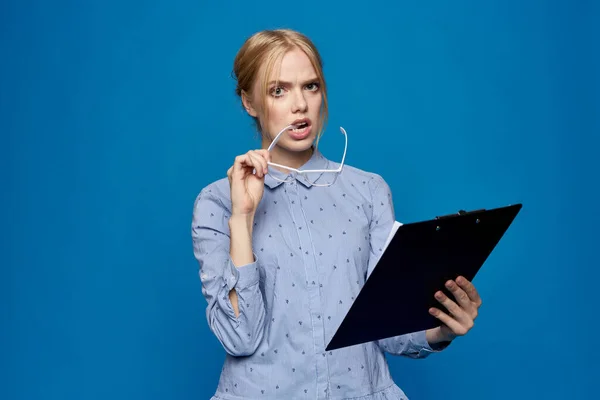 Mulher com uma pasta na mão em um fundo azul em uma camisa trabalho oficial — Fotografia de Stock