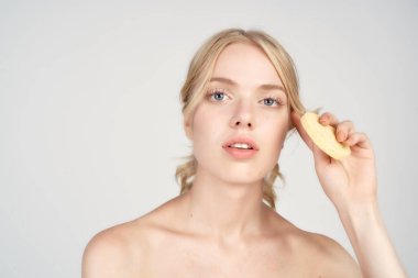 Çıplak omuzlu bir sarışın yüzüne pamuk pedleri tutar.