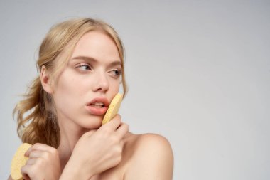 Çıplak omuzlu bir sarışın yüzüne pamuk pedleri tutar.