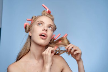 Çıplak omuzlu bir sarışın yüzüne pamuk pedleri tutar.