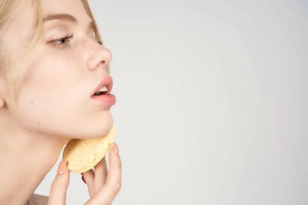 Eine Blondine mit nackten Schultern hält Baumwollkissen in der Nähe ihres Gesichts Hautpflege hellen Hintergrund — Stockfoto