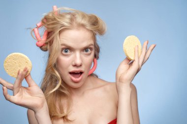 Çıplak omuzlu bir sarışın yüzüne pamuk pedleri tutar.