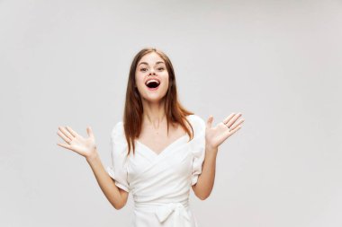 Kadın ellerini geniş gülüşünün önünde tutuyor beyaz elbisesi kırpık manzaralı 