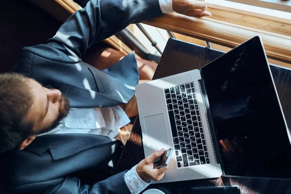 Uomo d'affari seduto in un caffè di fronte a un computer portatile documenti tazza di caffè esecutivo vista dall'alto tecnologia stile di vita — Foto Stock