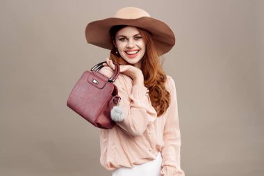  Bej makyajlı, şapkalı ve gömlekli kızıl saçlı kadın gülümsemesi gençleri cezbediyor.