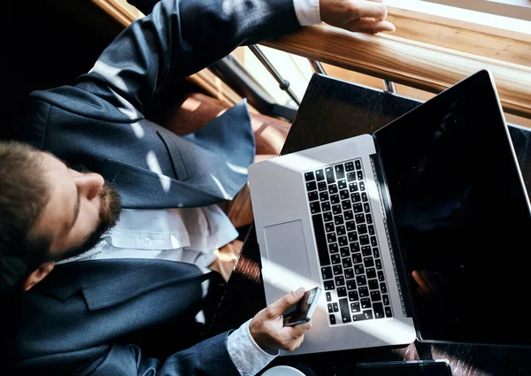 Επιχειρηματίας κάθεται σε ένα καφέ μπροστά από ένα laptop έγγραφα φλιτζάνι καφέ εκτελεστικό top view τρόπο ζωής της τεχνολογίας — Φωτογραφία Αρχείου