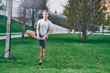 Spor adamı çimlerde fiziksel aktivite egzersizi yapıyor.