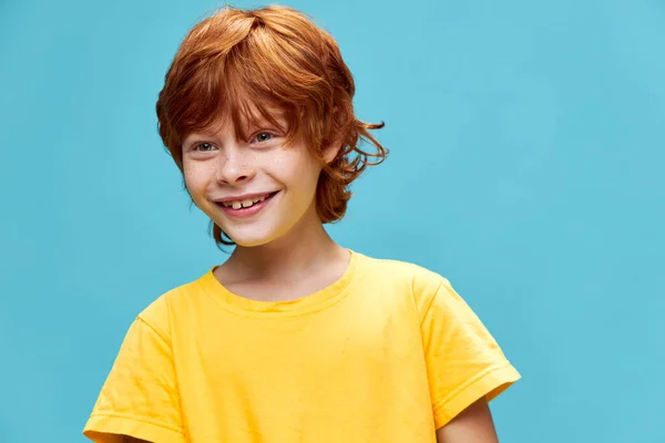 Παιδί σε κίτρινο T-shirt με κόκκινα μαλλιά και μπλε φόντο. — Φωτογραφία Αρχείου