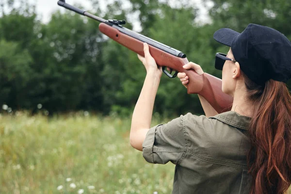 Mulher na natureza Mire com uma arma para cima caça para trás ver armas verdes — Fotografia de Stock