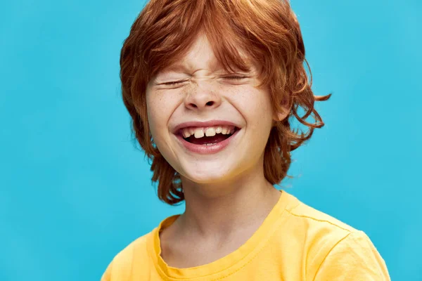 Červenovlasý chlapec se směje na modrém pozadí zblízka oříznutý pohled — Stock fotografie