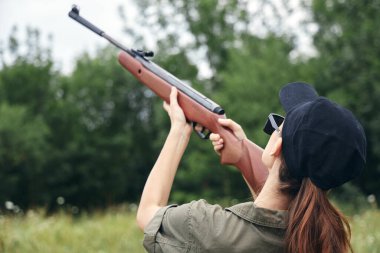 Doğadaki kadın silah avına çıkıyor. Siyah şapka, taze hava yeşili. 