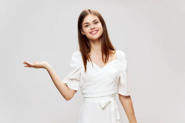 Woman in white dress holding palm in front of her smile cropped view studio — Stock Photo, Image