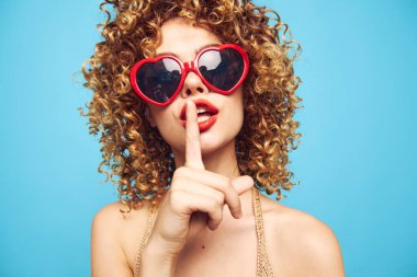 Mavi arka planda dans eden güzel sarışın, kırmızı güneş gözlüklü. 