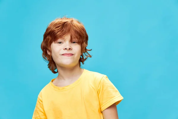 Przystojny chłopiec w żółtym t-shirt czerwone włosy niebieskie tło — Zdjęcie stockowe