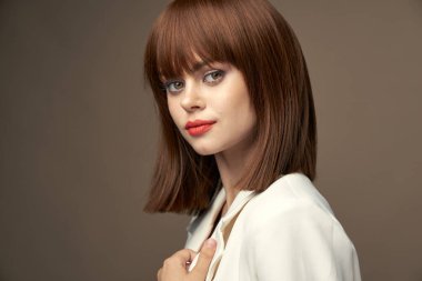 Açık renk ceketli güzel bir manken. El kol hareketleri yapıyor. 