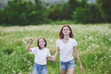 Genç anne ve kızı papatya tarlasında eğleniyorlar.