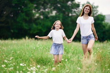 Genç anne ve kızı papatya tarlasında eğleniyorlar.
