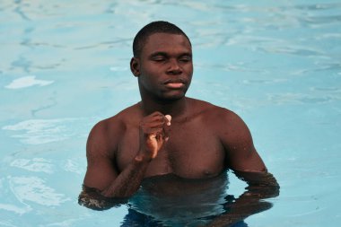 Havuzda poz veren genç yakışıklı adam.