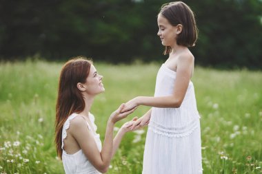 Genç anne ve kızı papatya tarlasında eğleniyorlar.