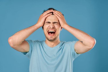 Stüdyoda mavi arka planda bağıran genç yakışıklı adam. 